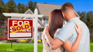 picture of couple looking at house with sold sign