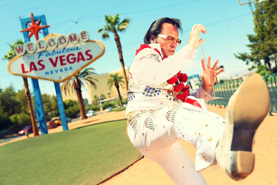 picture of Elvis look-alike impersonator man in front of Welcome to Fabulous Las Vegas sign on the strip. People having fun and Viva Las Vegas concept image with Elvis impersonator doing some crazy moves.