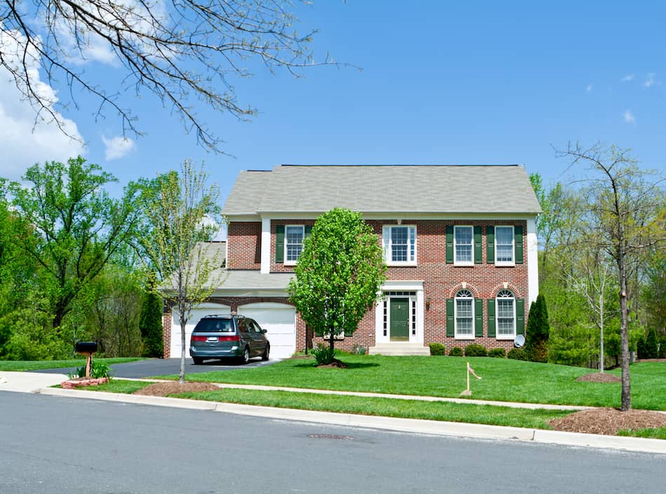 picture of Colonial style single family house in the Maryland suburbs.  House has a minivan parked on the driveway in front of a two car garage.