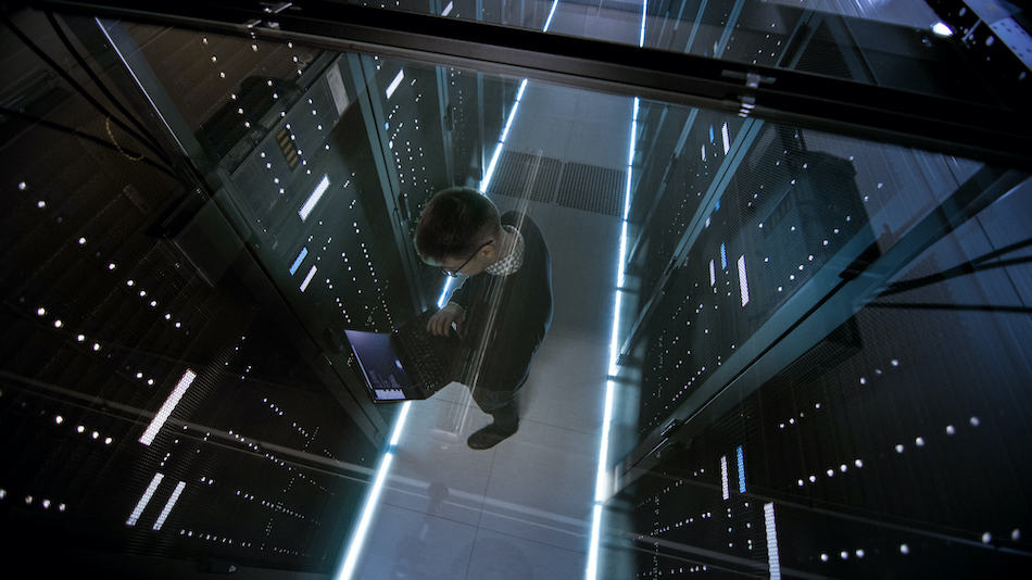 picture of Top View Through the Glass of IT Engineer Working with Laptop in Virginia Data Center Full of Active Rack Servers.