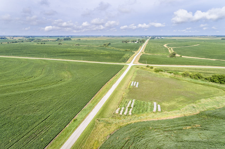 aerial view of rural Nebraska landscape with a farm road, soybean field and hay bales